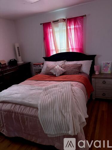A bed with a white comforter and a red pillow is in the image.
