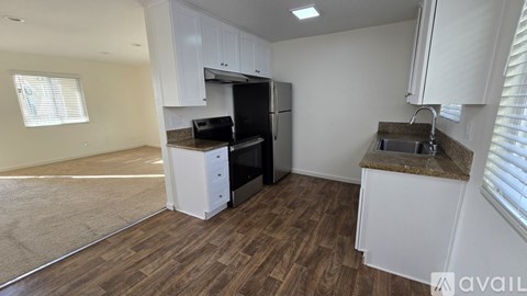A kitchen with white cabinets and a black fridge.