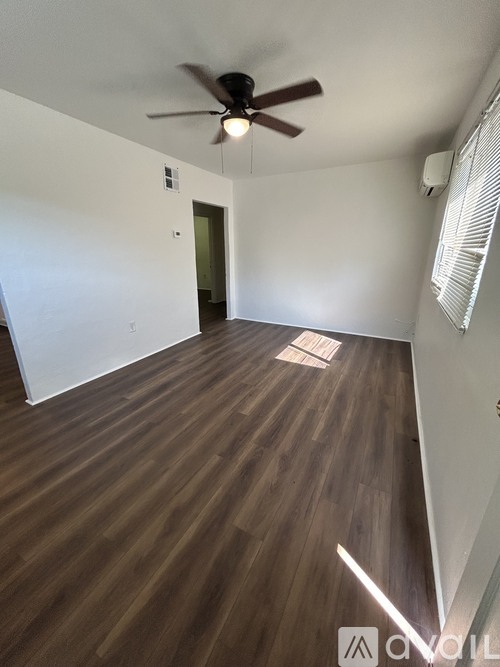 A room with a ceiling fan and wooden flooring.