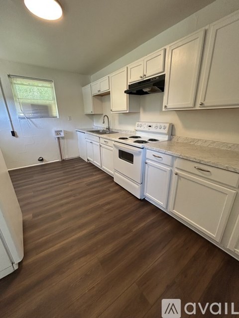 A kitchen with white appliances and wooden floors.