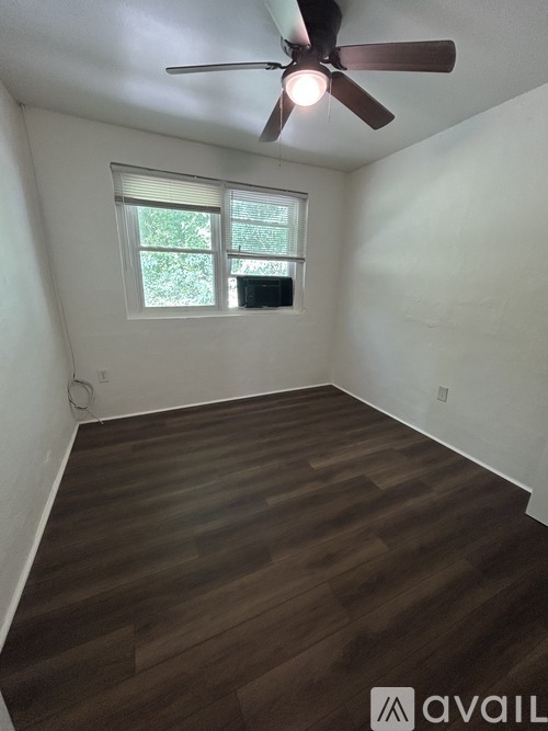 A room with a ceiling fan and wooden flooring.