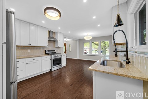 A modern kitchen with white cabinets and a wooden floor.