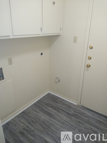 A room with a grey floor and white walls with a door and cabinets.
