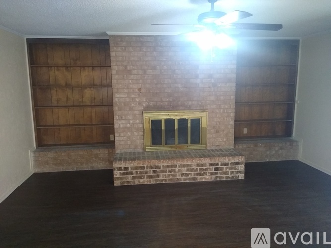 A room with a brick fireplace and wooden paneling on the wall.