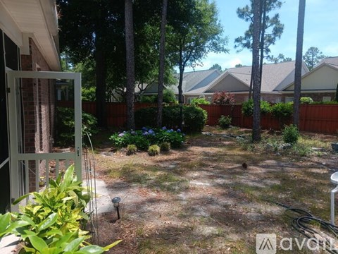 A backyard with a fence, trees, and a small garden.