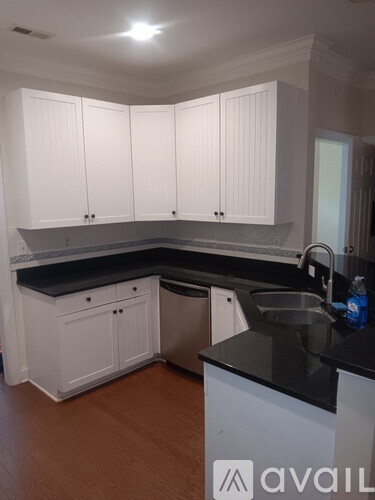 A kitchen with white cabinets and a black countertop.