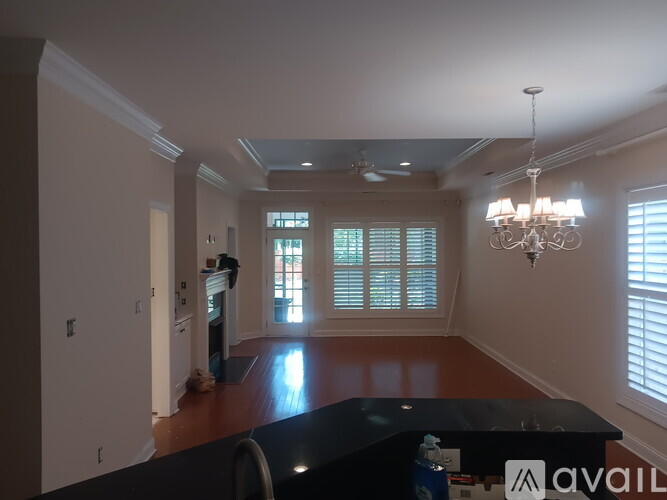 A living room with a chandelier, a fireplace, and a large window with blinds.