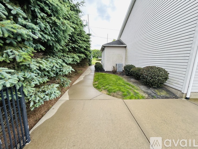 A sidewalk leads to a white building with a black fence on the left.
