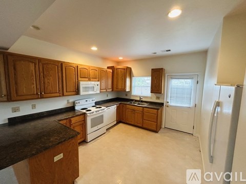 A kitchen with wooden cabinets and a black countertop.