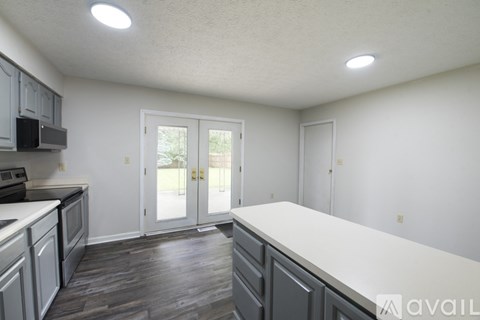 A kitchen with a white counter top and wooden floors.