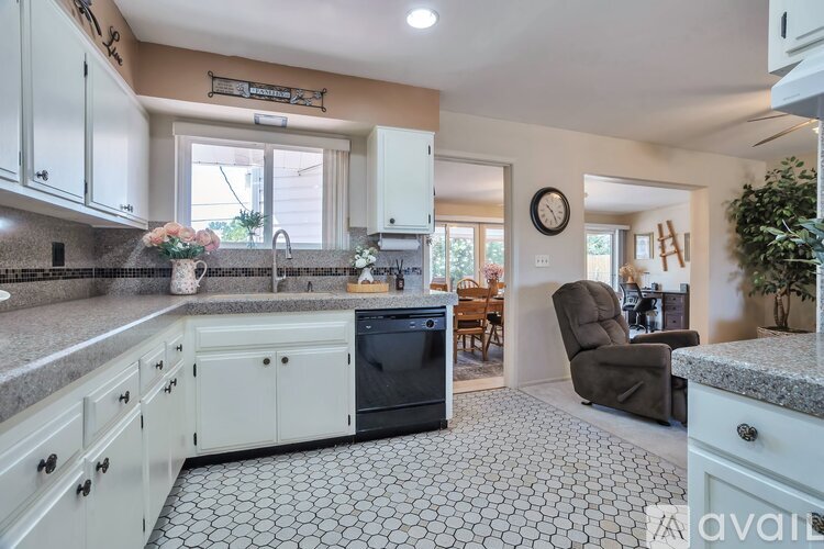 A kitchen with a black dishwasher and white cabinets.