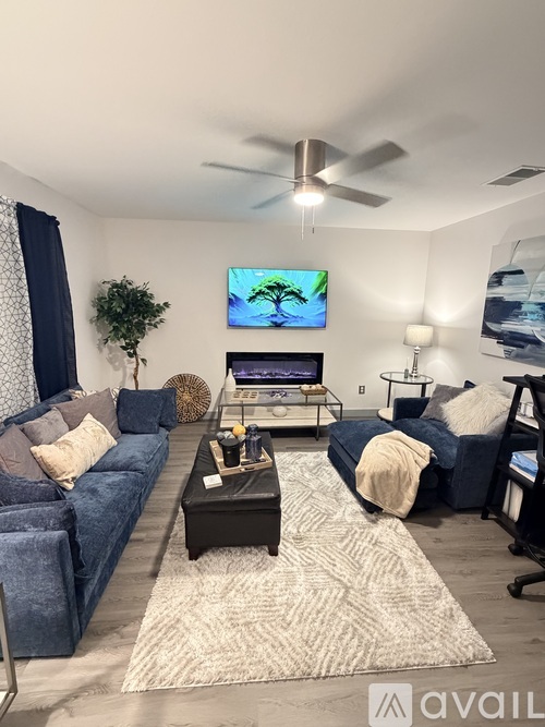A living room with a blue couch and a television on the wall.