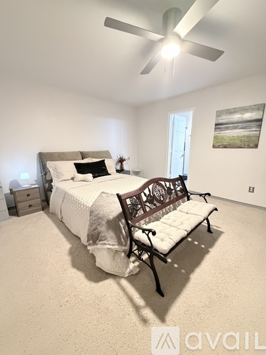 A bedroom with a bed, a bench, and a ceiling fan.