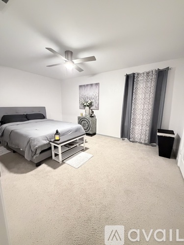 A bedroom with a bed, nightstand, and a ceiling fan.
