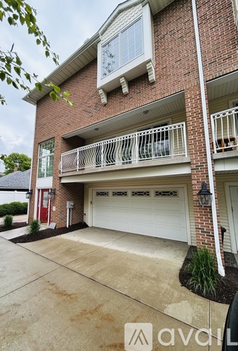 A two-story brick apartment building with a balcony and a garage door.