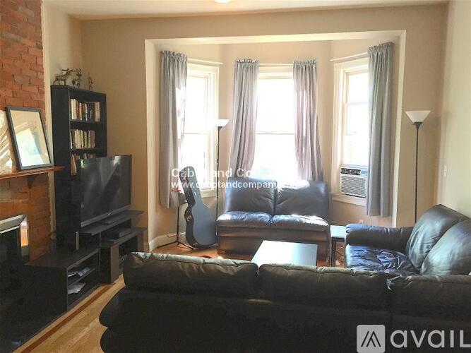 A living room with a black couch, a fireplace, and a television.