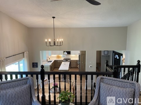 A living room with a sofa, chairs and a ceiling fan.