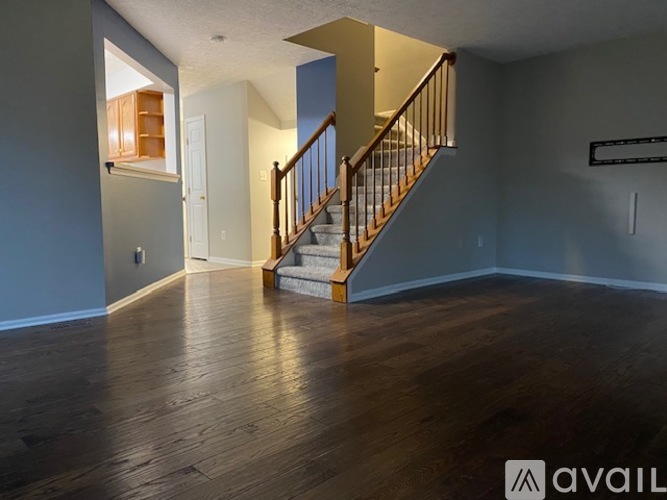 A spacious room with wooden floors and a staircase leading to another level.