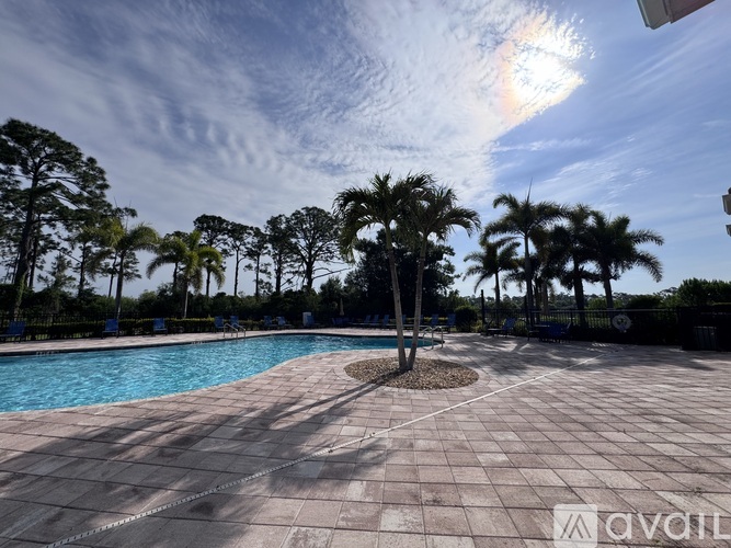 A pool surrounded by palm trees under a blue sky with a rainbow.