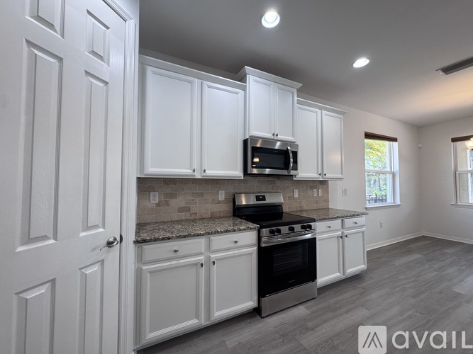 A kitchen with white cabinets and a granite countertop.