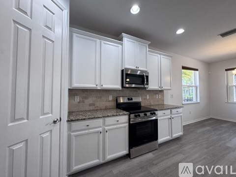 A kitchen with white cabinets and a granite countertop.