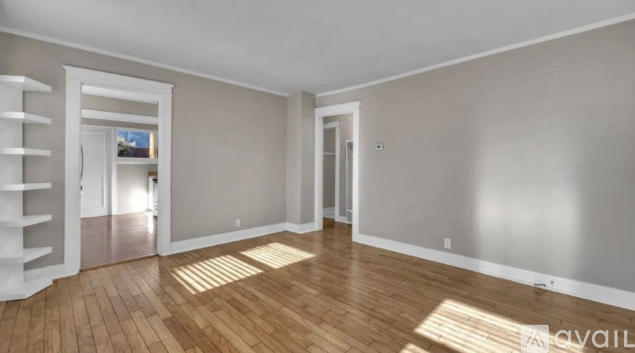 A spacious room with wooden floors and white walls.