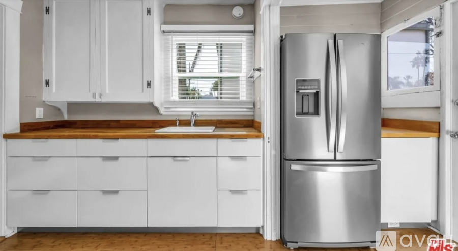 A modern kitchen with white cabinets and a stainless steel refrigerator.