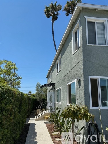 A grey house with a tree in front of it.