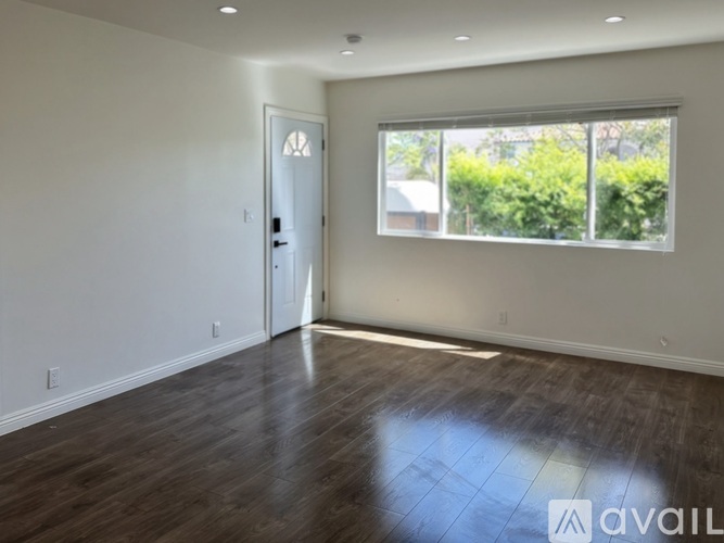 A room with a door and a window with a view of trees.