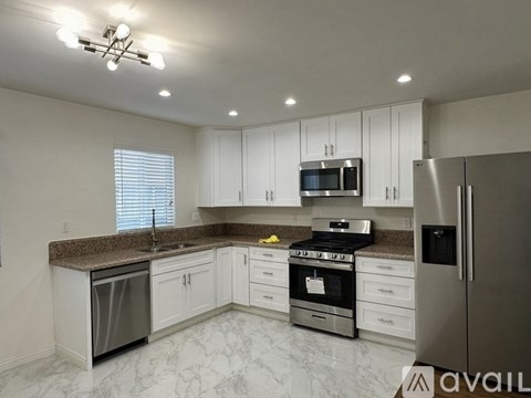 A kitchen with white cabinets and a granite countertop.