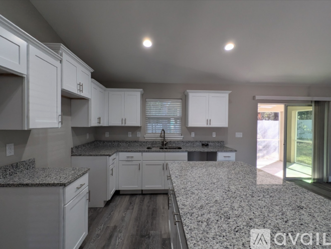 A kitchen with granite countertops and white cabinets.