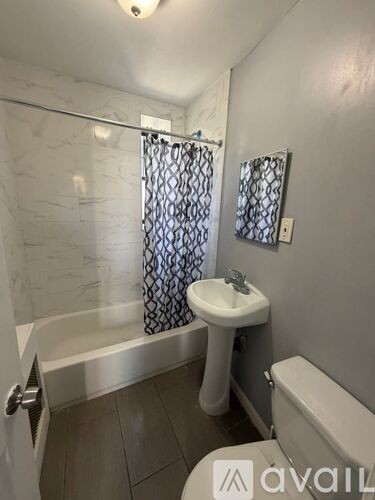 A bathroom with a white sink and a bathtub with a shower curtain.