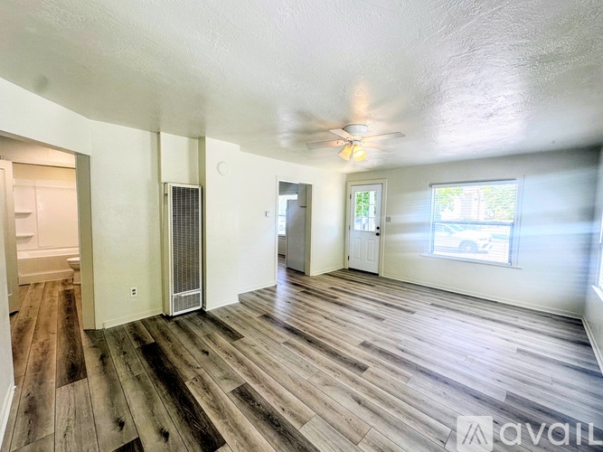 A spacious room with wooden flooring and a ceiling fan.