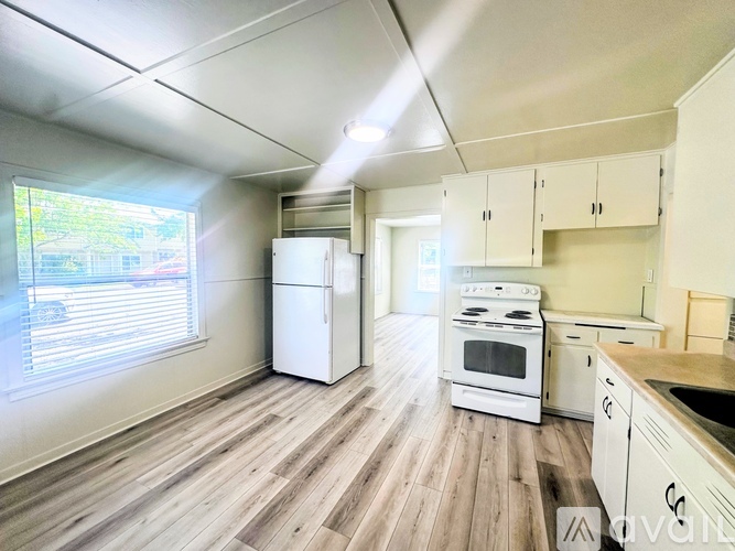 A kitchen with white appliances and wooden floors.