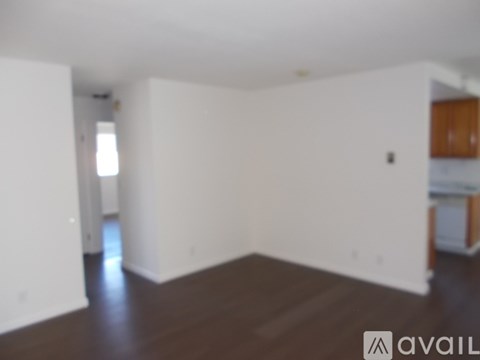 A room with white walls and wooden floors is available for rent.