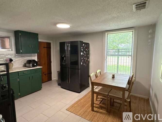 A kitchen with green cabinets and a black refrigerator.