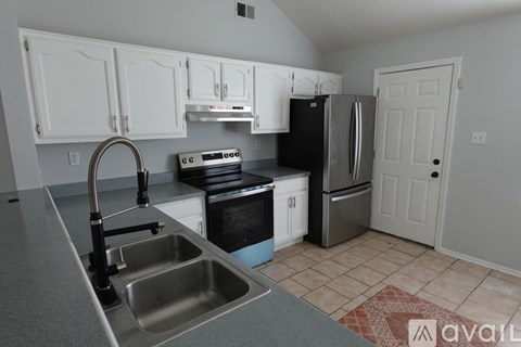 A kitchen with white cabinets and a black fridge.