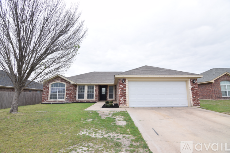 A house with a white garage door and a tree in front.