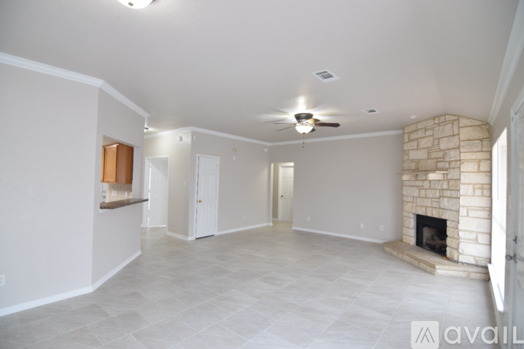 A spacious living room with a fireplace and a ceiling fan.