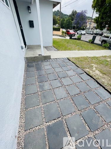 A grey paved walkway leads to a white building.
