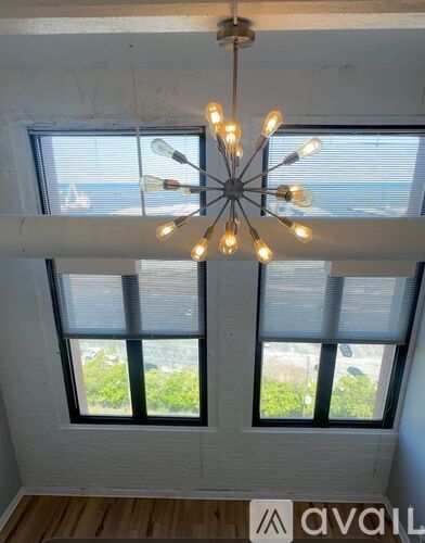 A chandelier with multiple lights hangs from the ceiling above a window with blinds.
