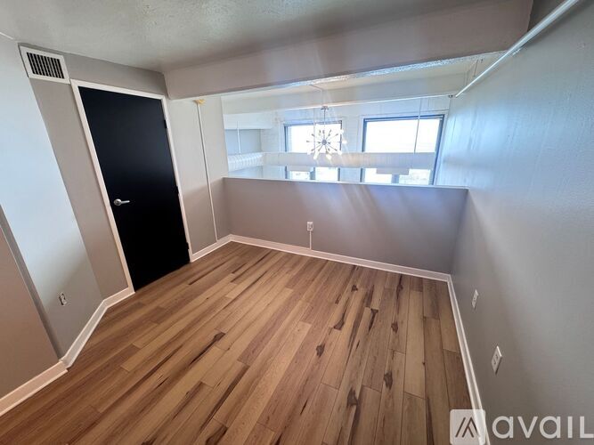 A room with wooden flooring and a black door.