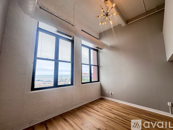 A room with wooden floors and two windows overlooking the sea.