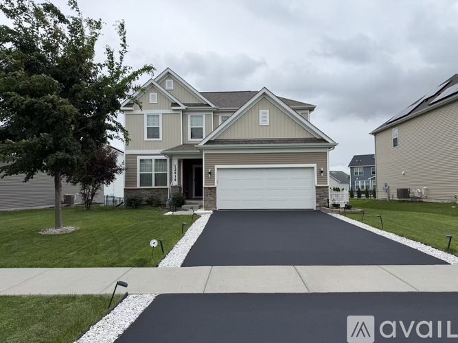 A two-story house with a garage and a driveway in front.