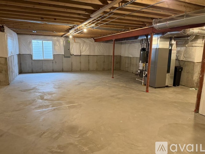 A spacious empty room with a concrete floor and a window on the left side.