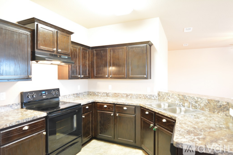 A kitchen with dark wood cabinets and granite countertops.