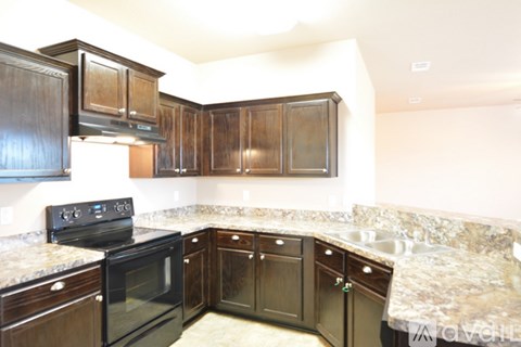 A kitchen with dark wood cabinets and granite countertops.