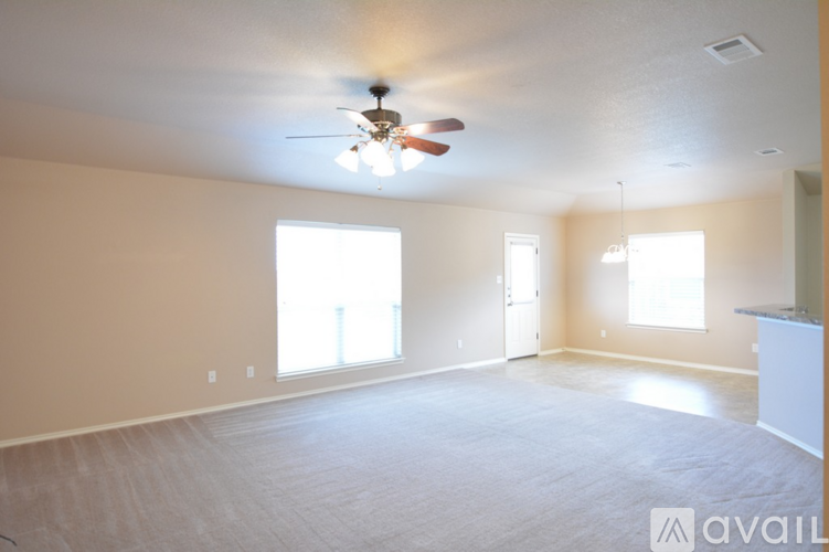A spacious room with a ceiling fan and two windows.