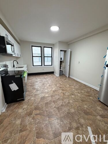 A kitchen with brown tiled flooring and white walls.