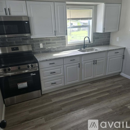 A kitchen with white cabinets and a black stove top oven.